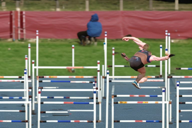 A person jumping over hurdles with determination on their face