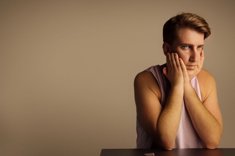 A person sitting at a desk with their hands folded together looking off into the distance with determination in their eyes