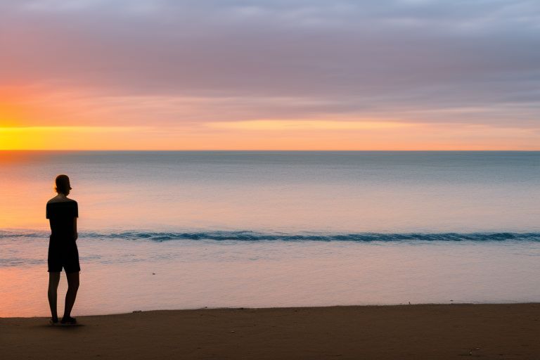 A person standing on a beach at sunset looking out into the horizon with a thoughtful expression on their face