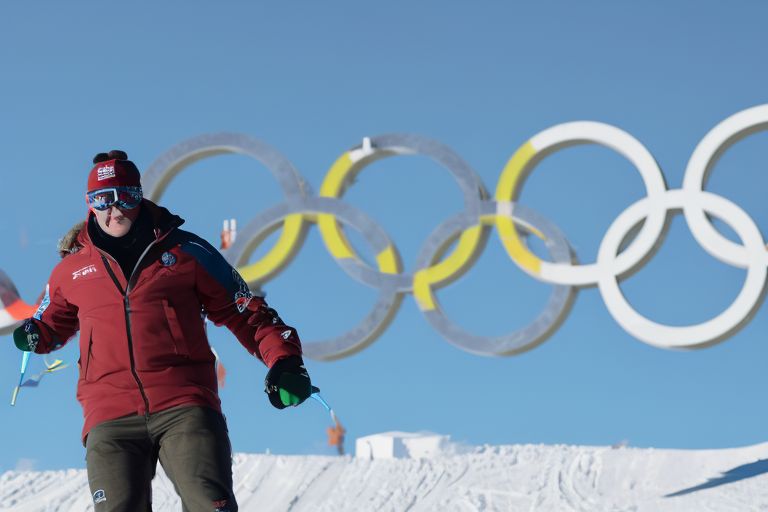 A photo of Sam Smith snowboarding with Olympic rings in the background