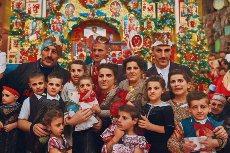A photo showing Serbian families celebrating St Nicholas' Day together with festive decorations in the background.