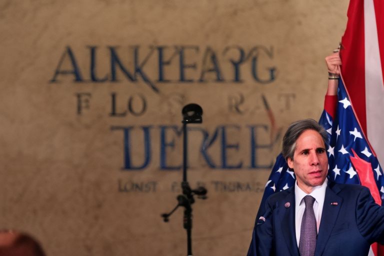 A picture of Antony Blinken standing before a podium with an American flag draped behind him, speaking into a microphone about his pledge of long-term aid for Turkey after devastating earthquakes.