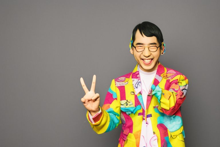A picture of Sakai Masato smiling while holding up two fingers in a peace sign gesture surrounded by bright colors