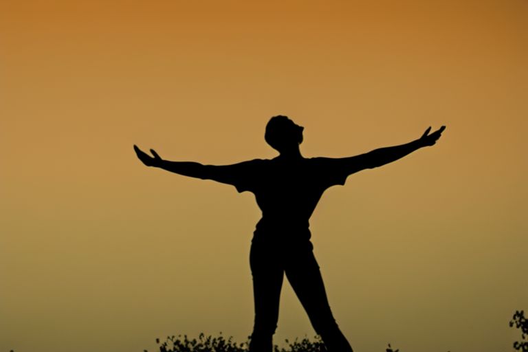 A silhouette of a person standing outside of their house, arms raised up in celebration against a bright yellow sky background.